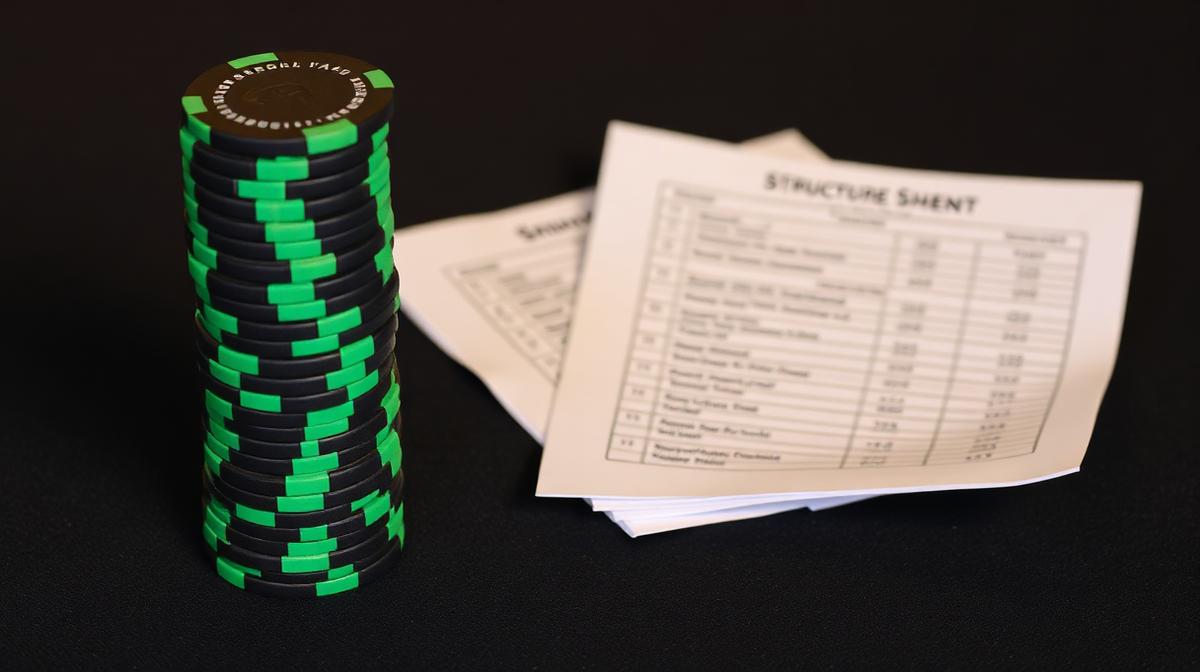 A tall stack of tournament chips next to a folded structure sheet